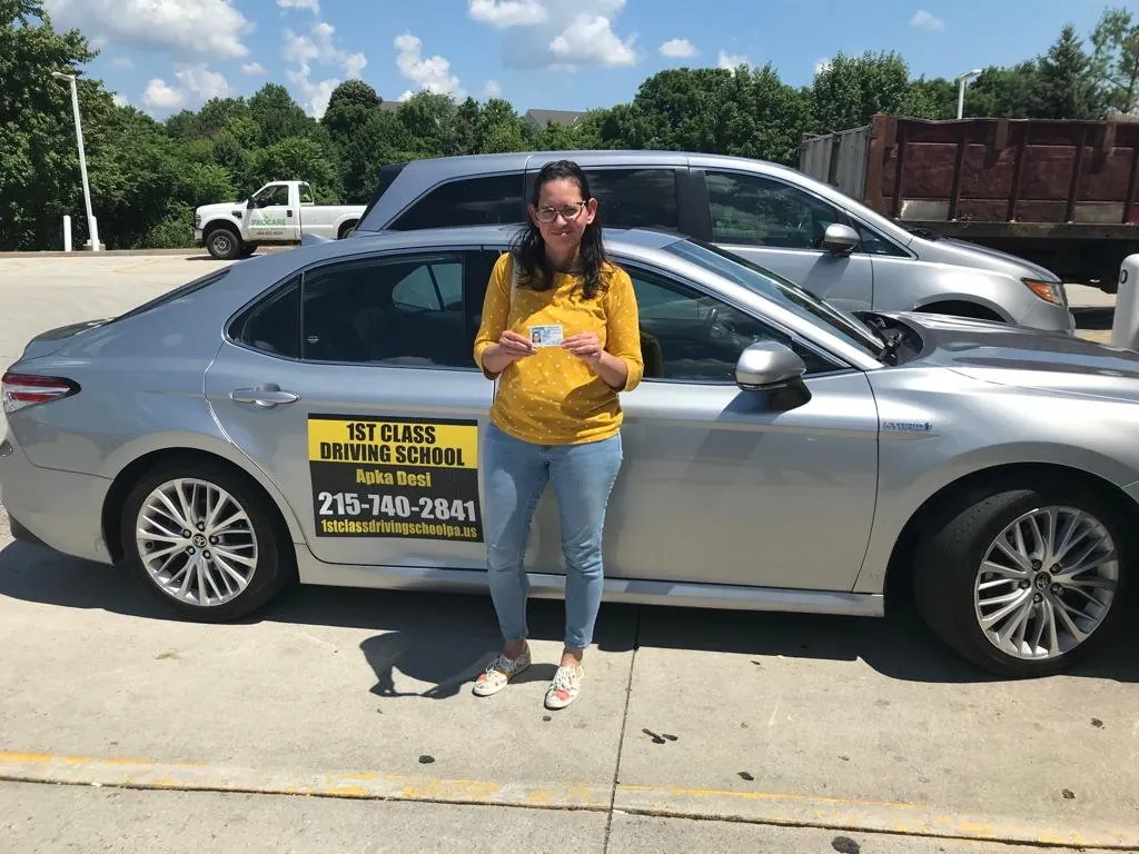 Student holding her documents next to the silver dual-control training car