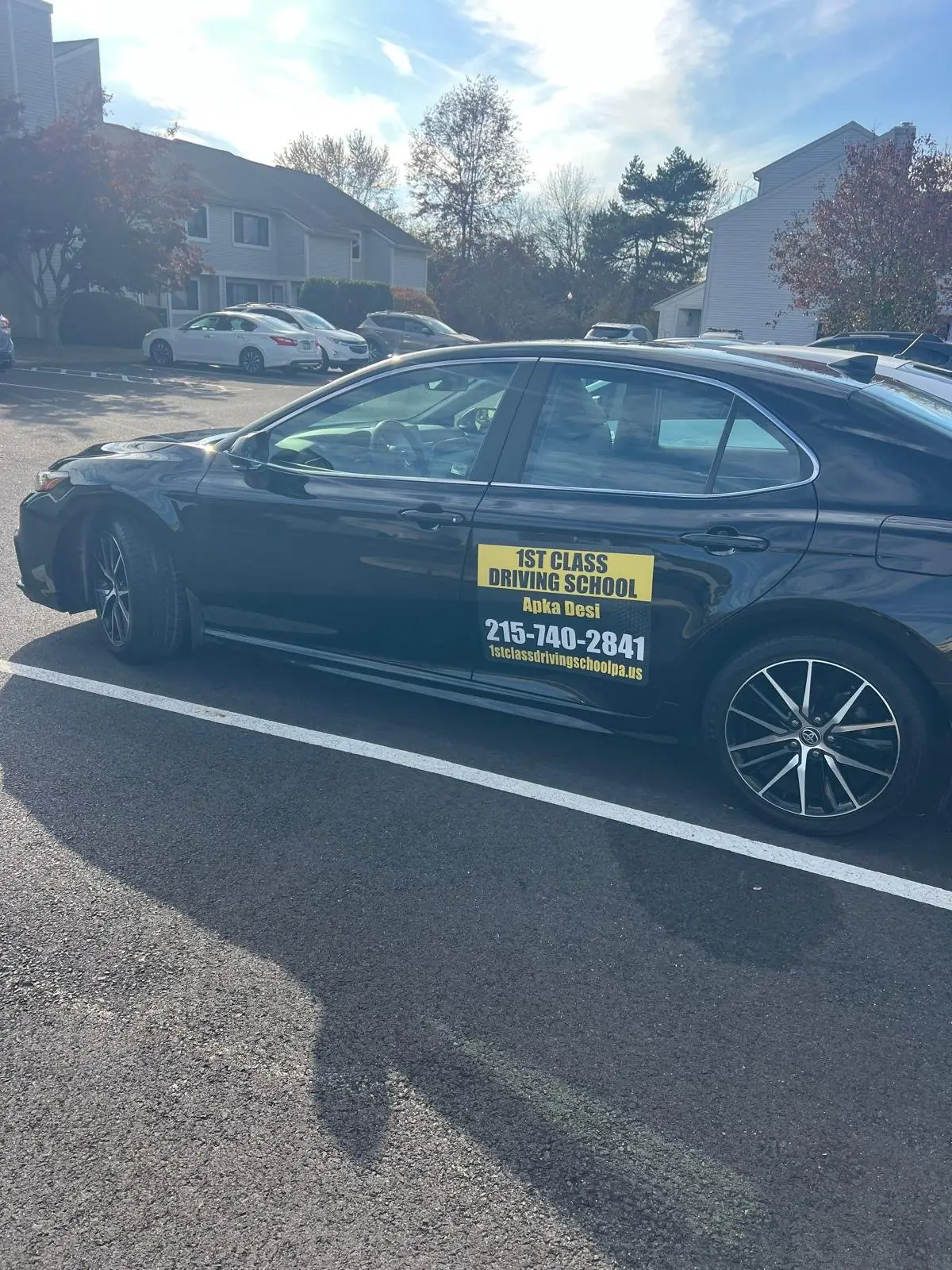 Dual-control training car parked under autumn trees between lessons
