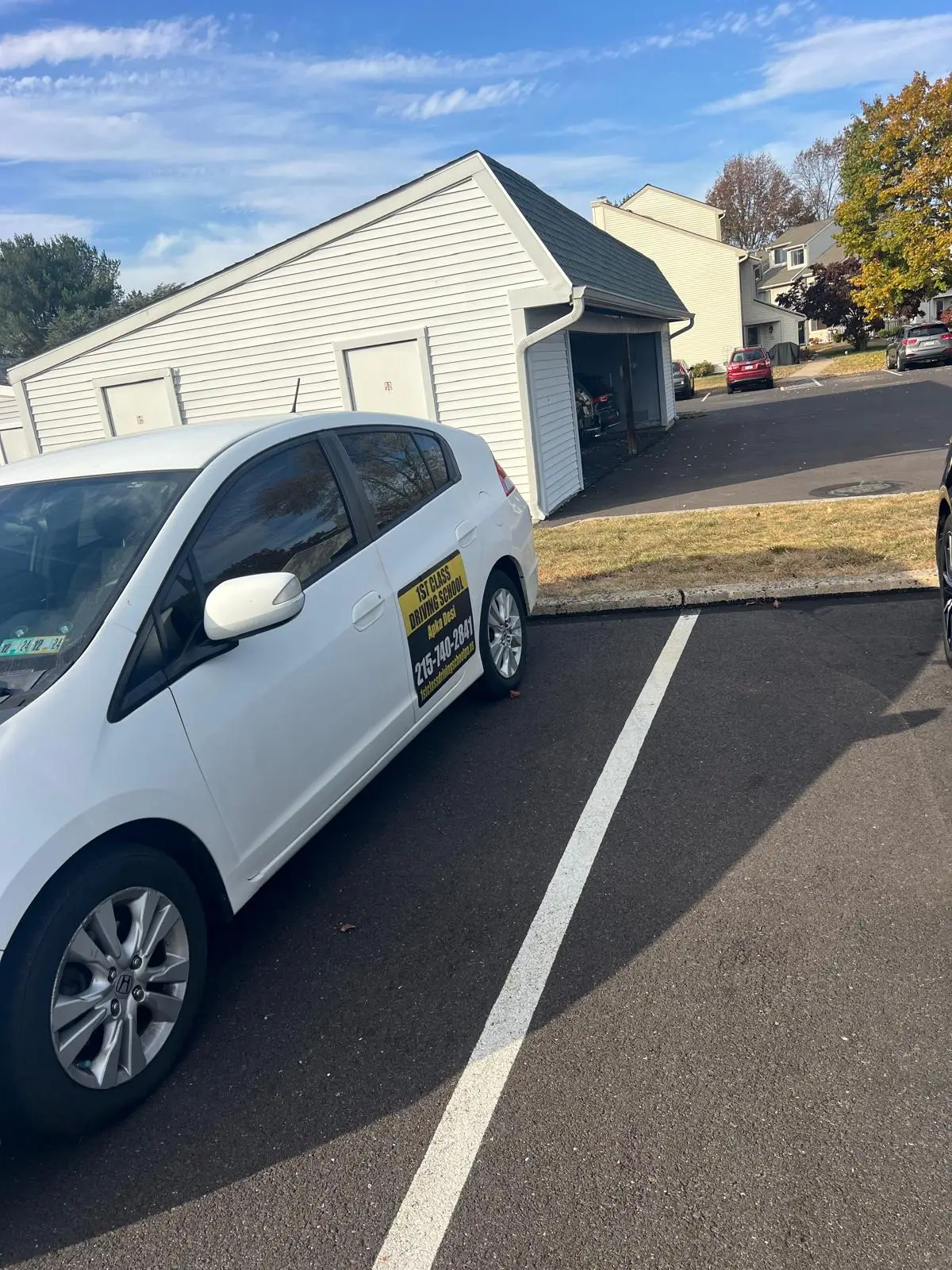 White training car parked beside a building on a lesson route